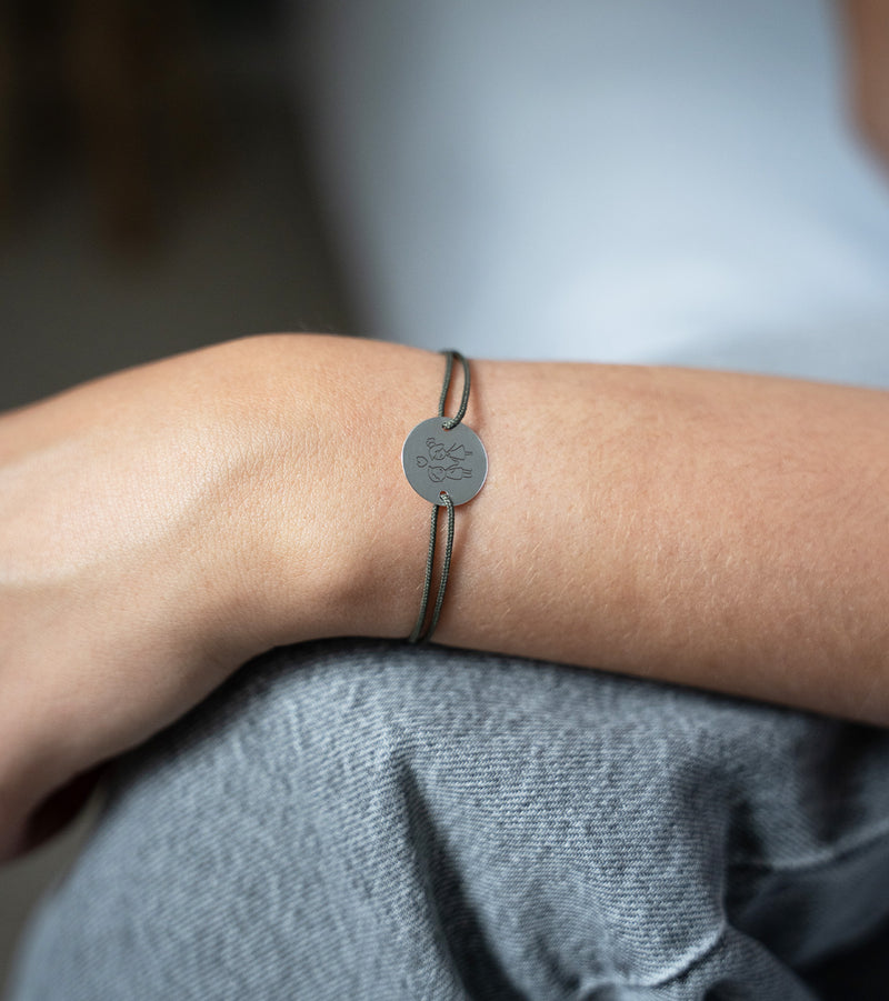 Élégant bracelet argenté avec une médaille personnalisée de 15mm, orné de deux trous distinctifs. Le cordon kaki ajoute une touche de sophistication à ce bijou unique.