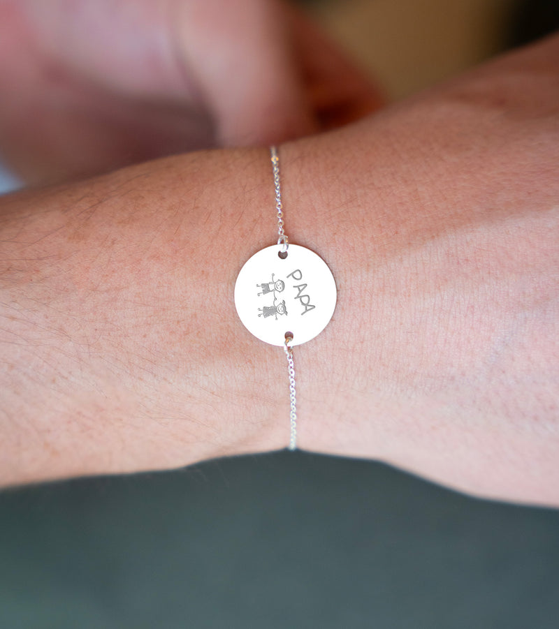 n bracelet argenté avec une médaille personnalisée de 20mm, munie de deux trous, montée sur une chaîne plate.