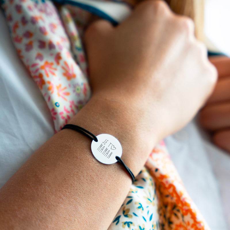 Ce bracelet, arborant une médaille argentée personnalisée de 20mm, deux trous pratiques, et un cordon noir