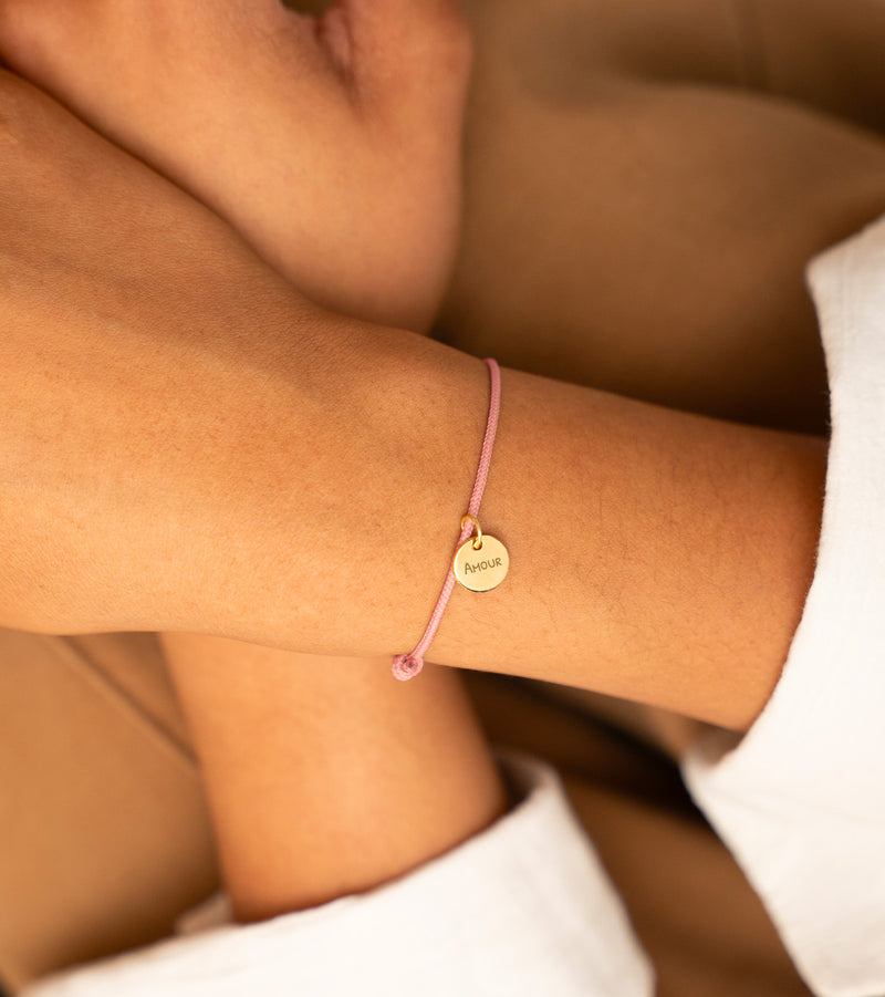 Bracelet en médaille plaqué or de 10mm sur cordon rose. Ajoutez une touche de sophistication à votre tenue.