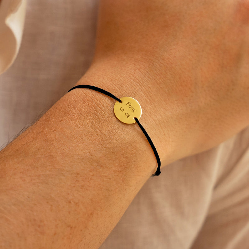 Bracelet, agrémenté d'une médaille personnalisée de 15mm en plaqué or et d'un cordon noir.