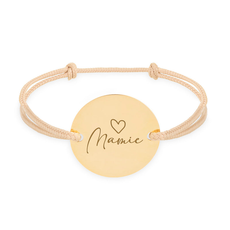 Ce bracelet personnalisé, doté d'une médaille de 20mm, de deux trous en plaqué or et d'un cordon beige, incarne l'élégance