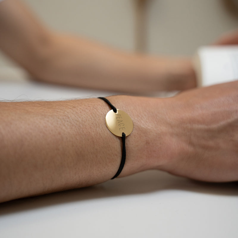 Avec une médaille personnalisée en 20mm, ce bracelet comprend deux trous en plaqué or et un cordon noir, soulignant son caractère unique.