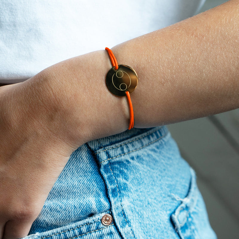 Un cordon orange fluo accompagne ce bracelet médaille, personnalisé en 20mm avec deux trous en plaqué or.