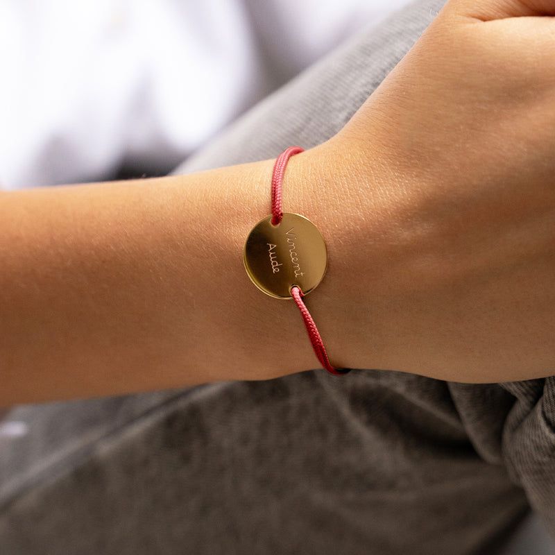 bracelet médaille en 20mm, orné de deux trous en plaqué or et agrémenté d'un cordon rouge.