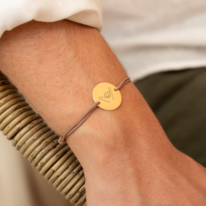 une médaille personnalisée en 20mm, ce bracelet est doté de deux trous en plaqué or et d'un cordon marron clair.