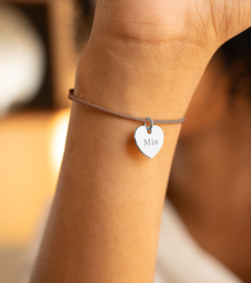 Voici une image d'un bracelet coeur de 15mm en argent, personnalisé, avec un cordon de couleur marron clair.