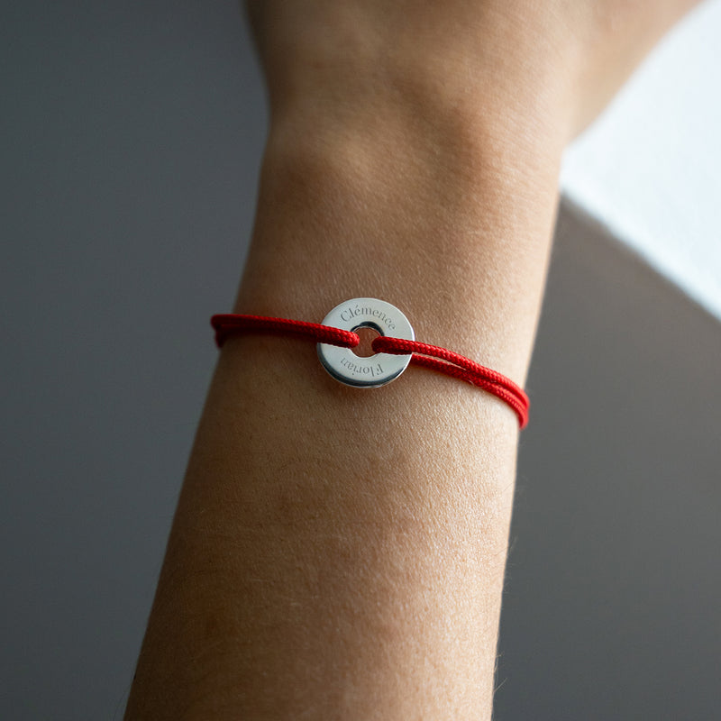 Le cordon rouge met en valeur ce bracelet en forme de cible, personnalisé de 15mm en argent.