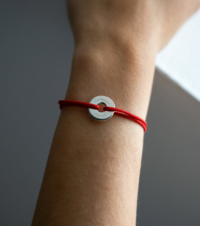 Le cordon rouge met en valeur ce bracelet en forme de cible, personnalisé de 15mm en argent.