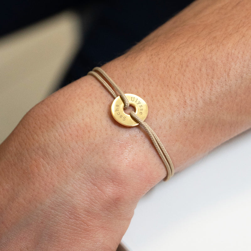 En forme de cible et avec un cordon beige, ce bracelet personnalisé en 15mm est plaqué or