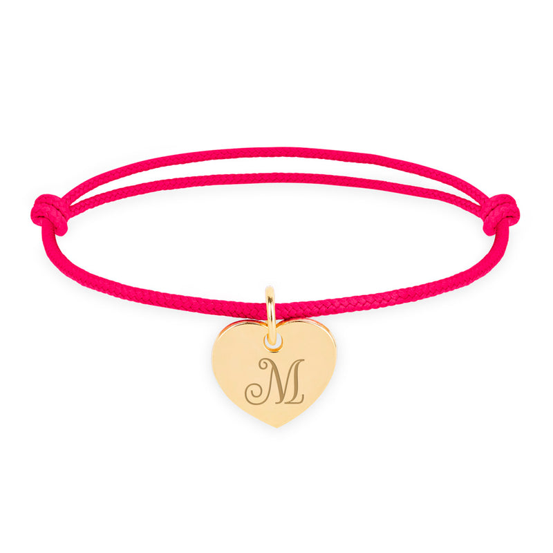 Un bracelet en plaqué or, agrémenté d'un cœur de 15mm, accompagné d'un cordon rose fuchsia.