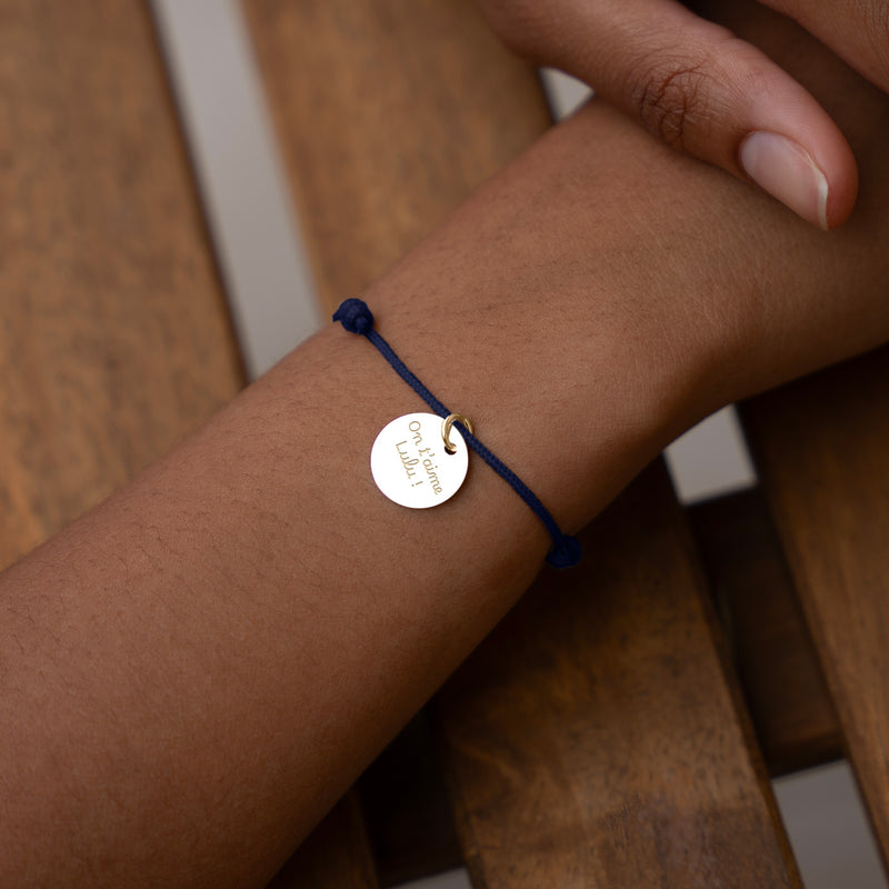 Un bracelet unique, une médaille de 15mm en plaqué or associée à un cordon bleu marine, pour un style distingué.