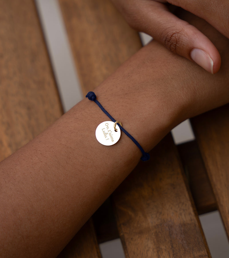 Un bracelet unique, une médaille de 15mm en plaqué or associée à un cordon bleu marine, pour un style distingué.