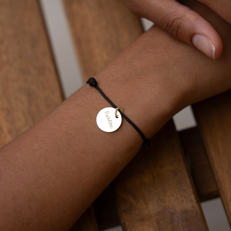 Un bracelet en plaqué or avec une médaille de 15mm, monté sur un cordon noir élégant.