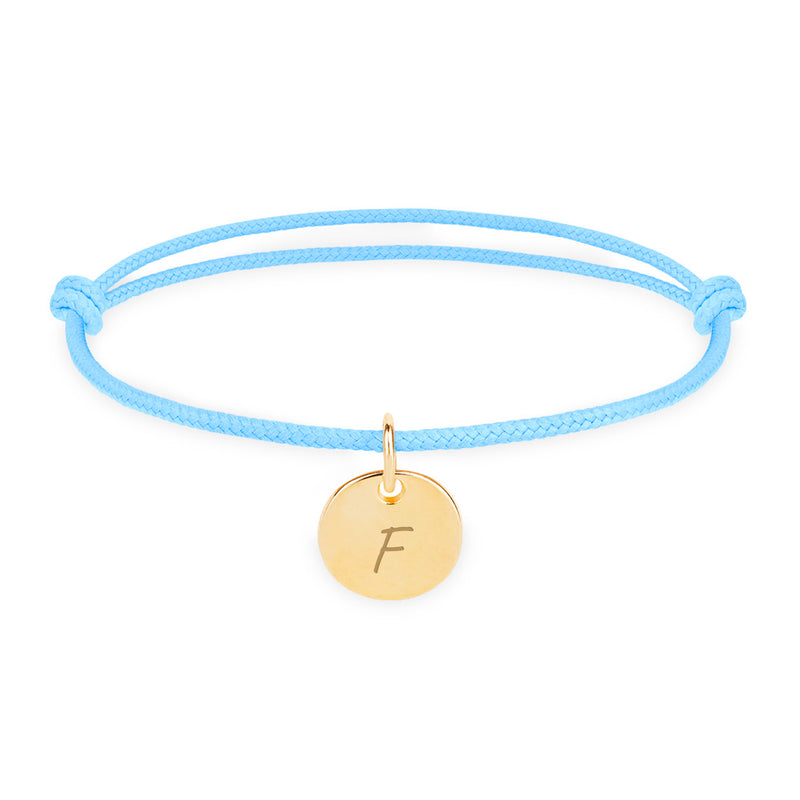 Un bracelet personnalisé en plaqué or, avec une médaille de 10mm, sur un cordon bleu pastel.