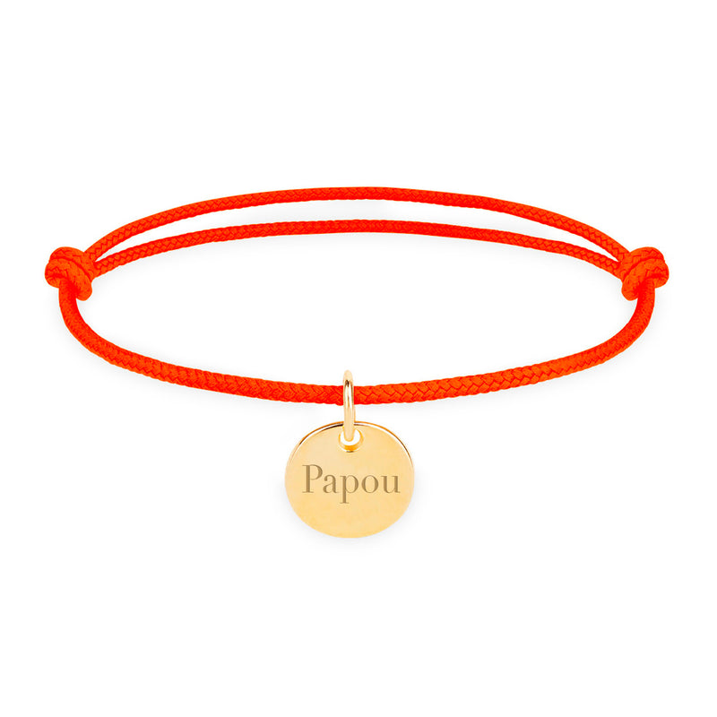 Une médaille dorée brillante suspendue à un cordon orange fluo.