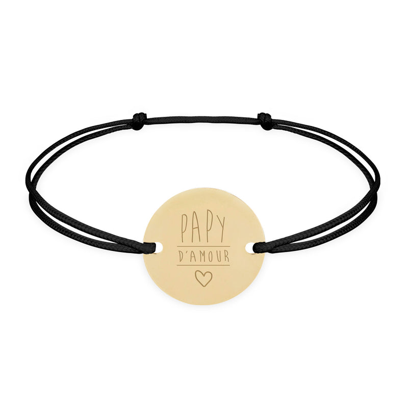 Un bracelet, orné d'une médaille de 15mm, doté de 2 trous et plaqué or. Son cordon noir ajoute une touche de sobriété