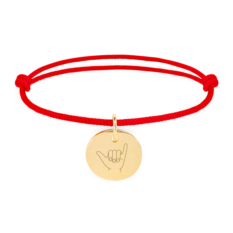 Un bracelet personnalisé avec une médaille de 15mm, plaqué or, sur un cordon rouge.