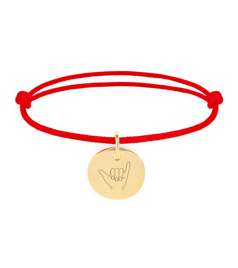 Un bracelet personnalisé avec une médaille de 15mm, plaqué or, sur un cordon rouge.