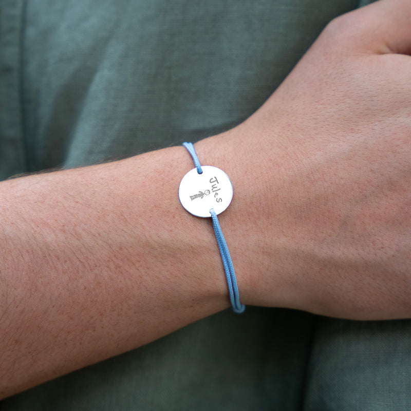 Le bracelet médaille, personnalisé en 20mm, se caractérise par ses deux trous en plaqué argent et son cordon bleu pastel.