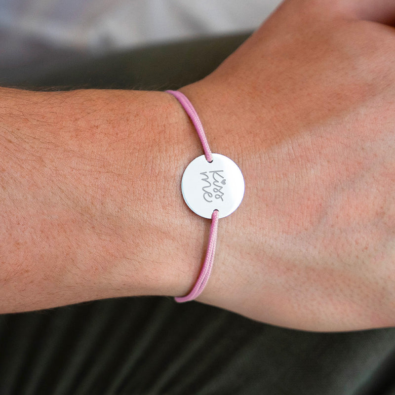 Ce bracelet, incluant une médaille personnalisée de 20mm, est orné de deux trous argent et d'un cordon rose élégant.