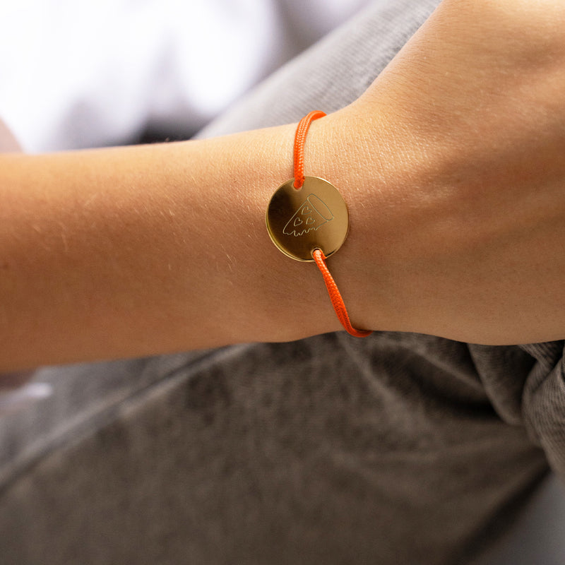 un bracelet médaille unique, personnalisé en 20mm, avec deux trous en plaqué or et un cordon orange fluo.