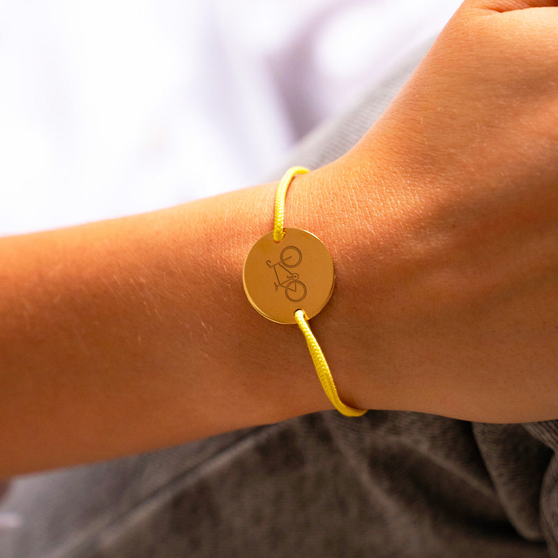 Pédalez en toute élégance ! Ce bracelet en plaqué or, orné d'un cordon jaune, est le cadeau idéal pour les cyclistes passionnés. Personnalisez-le pour un souvenir qui roule !