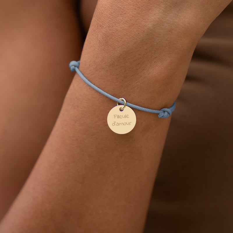 Apportez une touche d'élégance à votre tenue avec ce bracelet en cordon bleu pastel, accompagné d'une médaille plaquée or de 15mm.