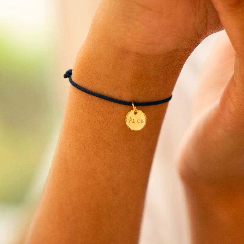 Superbe bracelet personnalisé. Une médaille plaquée or 10mm, montée sur cordon bleu marine.
