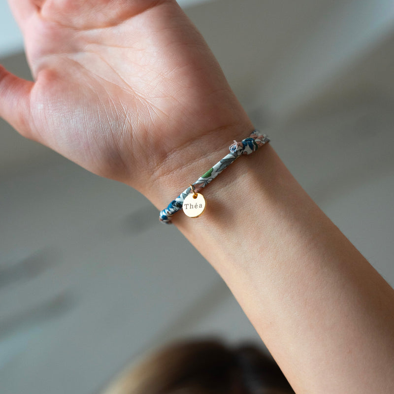 Un bracelet personnalisé avec une médaille de 10mm en plaqué or, agrémenté d'un lien Liberty lilas.