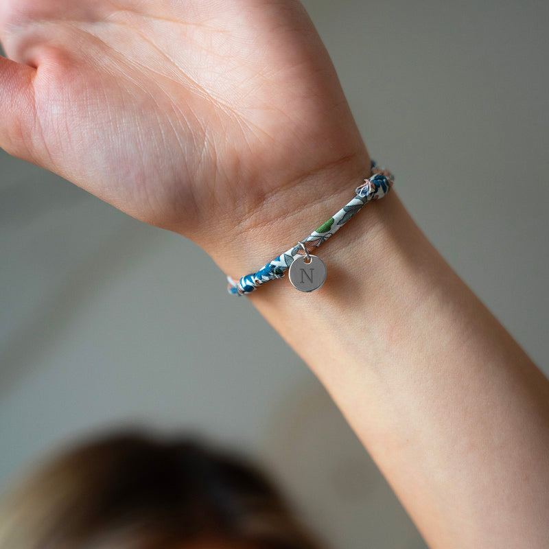 Un bracelet argenté, rehaussé d'une médaille de 10mm, enveloppée dans un ravissant Liberty Lilas.