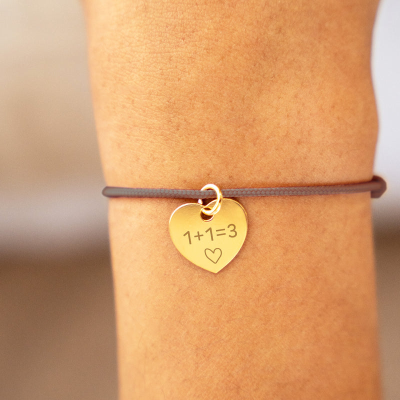 Un bracelet en forme de cœur, plaqué or de 15mm, accentué par un cordon marron clair.