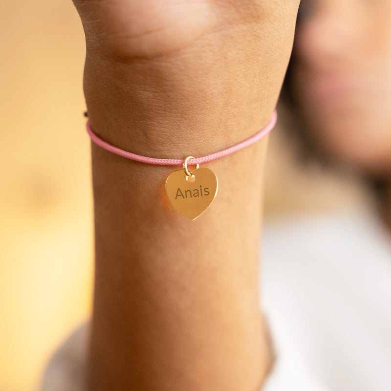 Bracelet en plaqué or avec un cœur et un cordon rose.