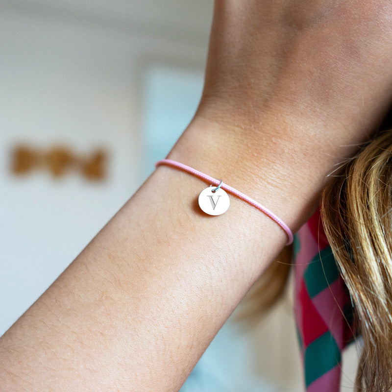 Un bracelet argenté, médaille de 10mm, sur cordon rose. Un style moderne.