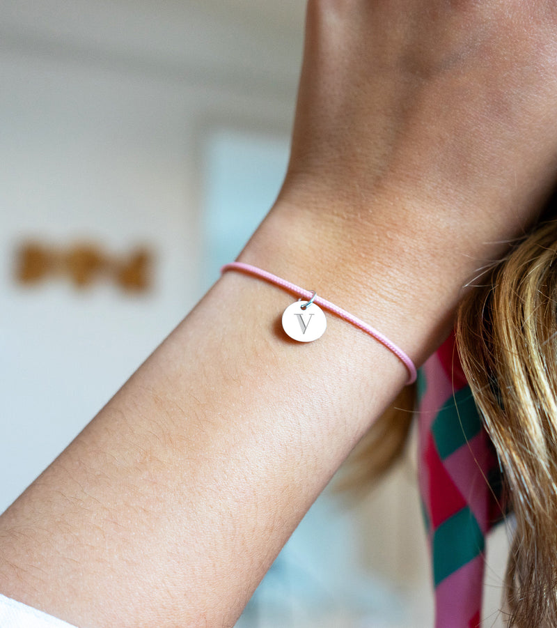 Un bracelet argenté, médaille de 10mm, sur cordon rose. Un style moderne.