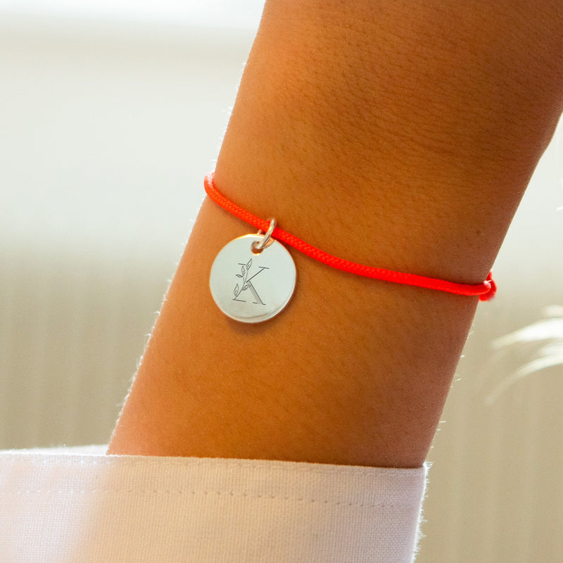 Bracelet argenté avec médaille de 15mm et cordon orange fluo. Une fusion de style moderne et de couleur vibrante.