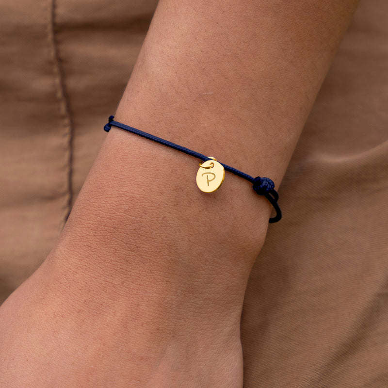 Charmant bracelet avec médaille de 10mm en plaqué or, sur cordon bleu marine.