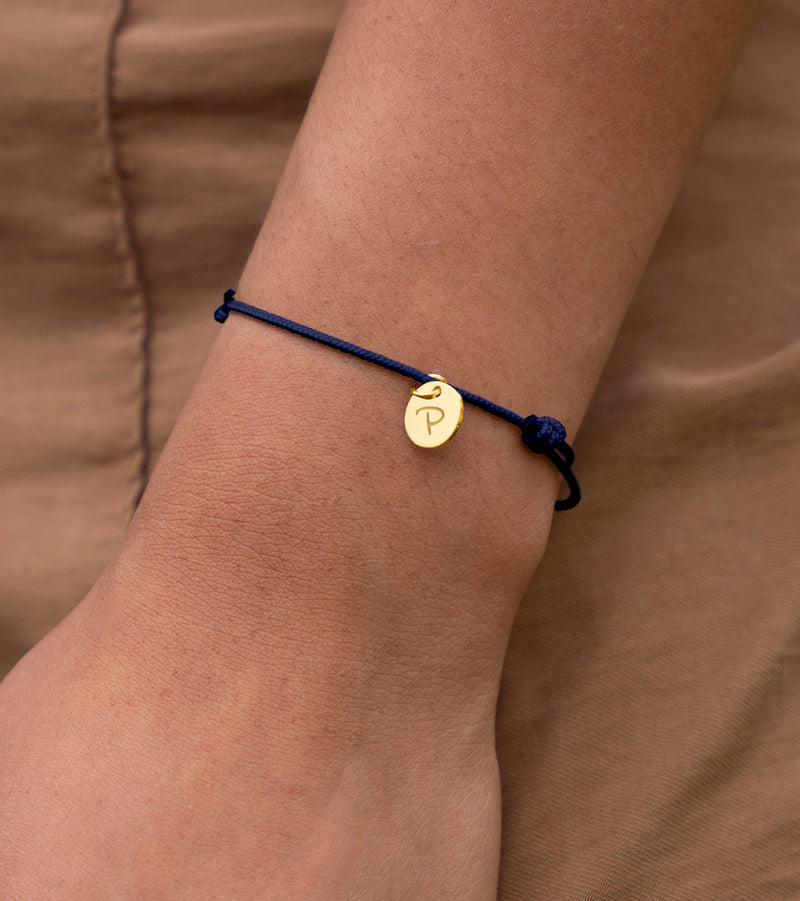 Charmant bracelet avec médaille de 10mm en plaqué or, sur cordon bleu marine.