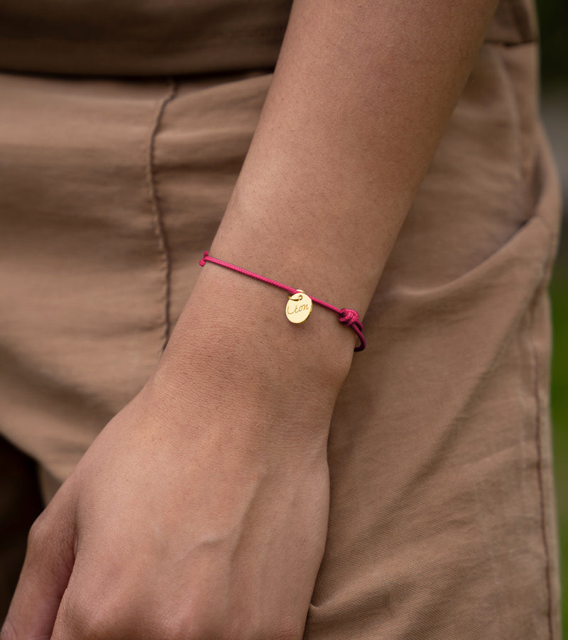 Une médaille plaquée or de 10mm suspendue à un bracelet en cordon rose fuchsia.