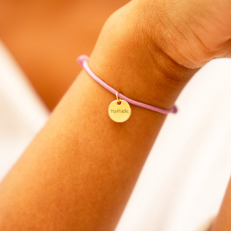 Bracelet médaille plaqué or sur cordon rose. Sublimez votre poignet avec cet accessoire raffiné.