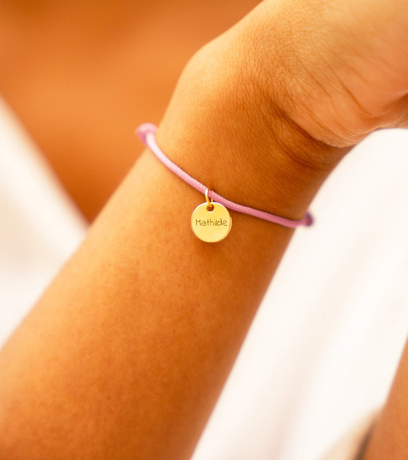 Bracelet médaille plaqué or sur cordon rose. Sublimez votre poignet avec cet accessoire raffiné.