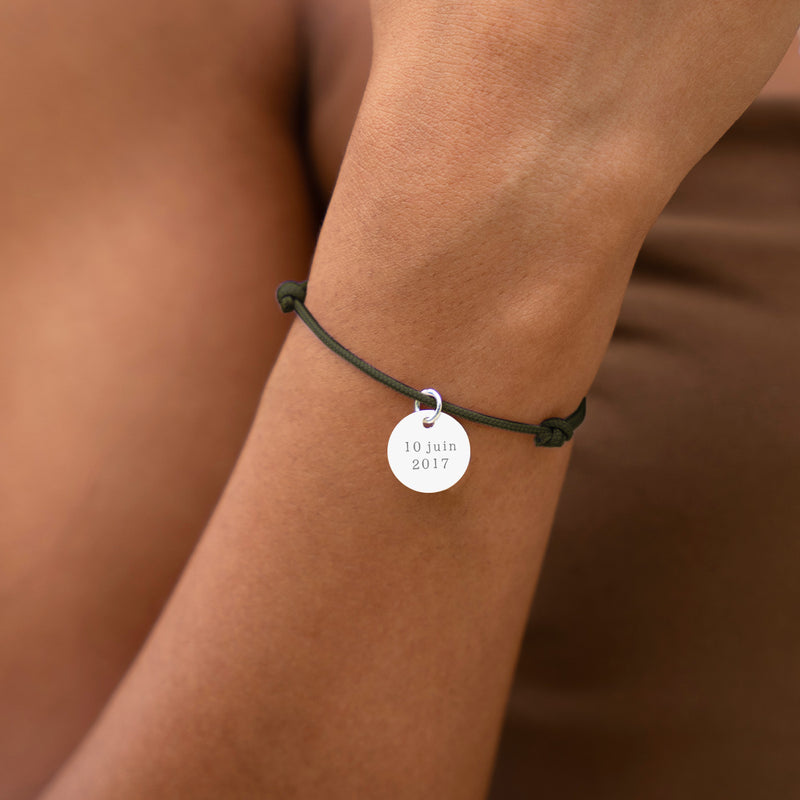 Bracelet en argent orné d'une médaille de 15mm, attaché à un cordon kaki.