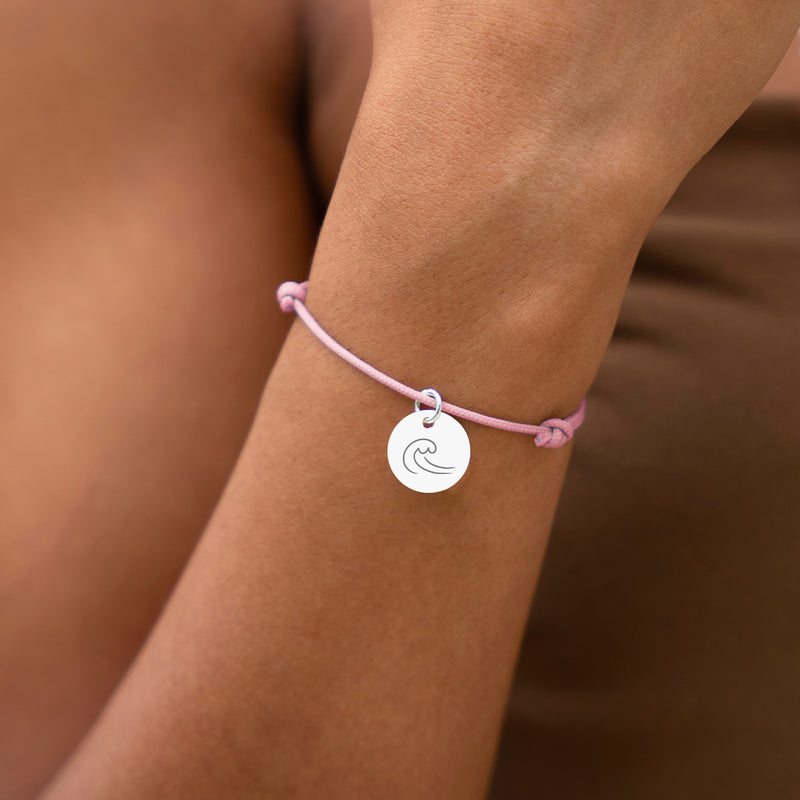 Un bracelet argenté avec une médaille de 15mm sur un cordon rose.