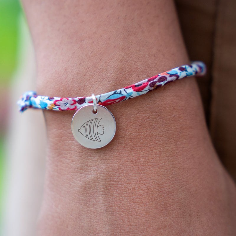 Bijou argenté agrémenté d'une médaille de 15mm, lié par un élégant Liberty Pavot.