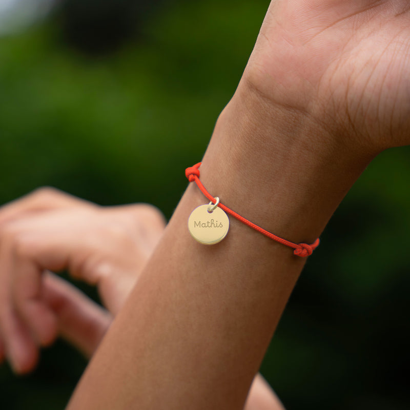 Mettez en valeur votre look avec ce bracelet personnalisé, comprenant une médaille plaquée or de 15mm sur un cordon orange fluo.