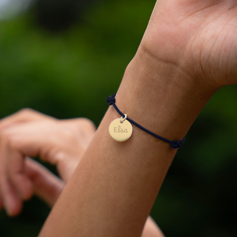 Médaille de 15mm plaqué or sur bracelet personnalisé, accentué par un cordon bleu marine, ajoutant une note sophistiquée.