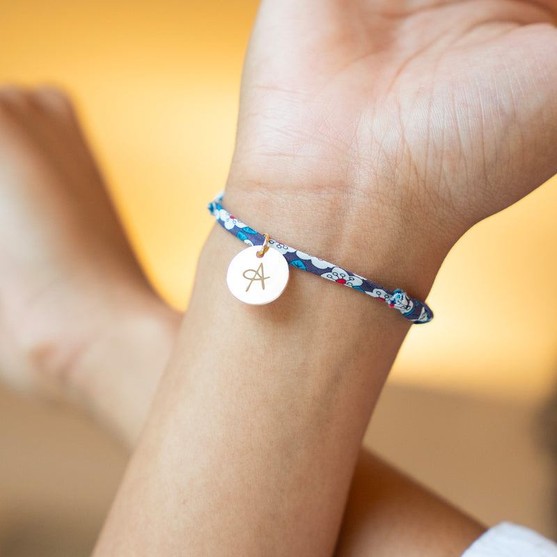 Charmant bracelet avec une médaille de 15mm en plaqué or, attachée à un lien Liberty Iris.