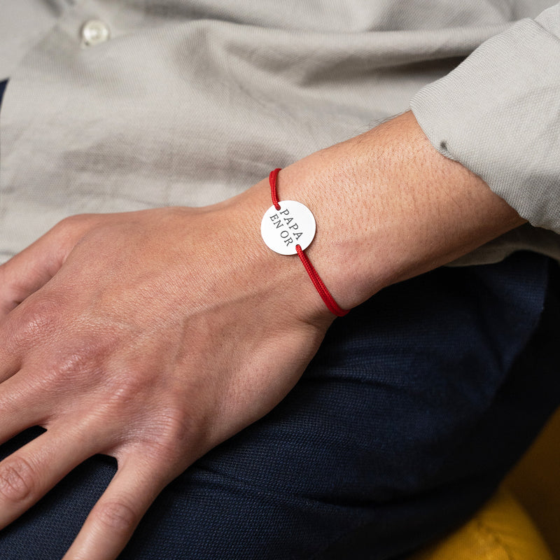 Sur cordon rouge, ce bracelet médaille en plaqué argent, personnalisé et doté de deux trous, ajoute une touche d'élégance.