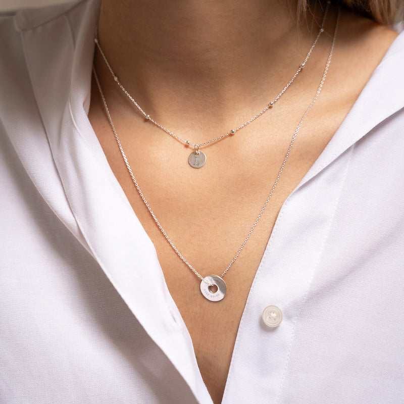 Un pendentif en forme de cible, personnalisé de 15mm en argent, assure une allure unique.