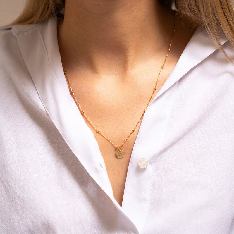 Un charmant pendentif de 10mm en plaqué or, orné de votre inscription préférée, pour une pièce unique qui vous distingue.